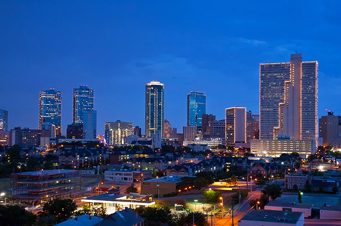 Fort Worth skyline at dusk with illuminated buildings, representing a vibrant business environment for FileMaker Pro development solutions.